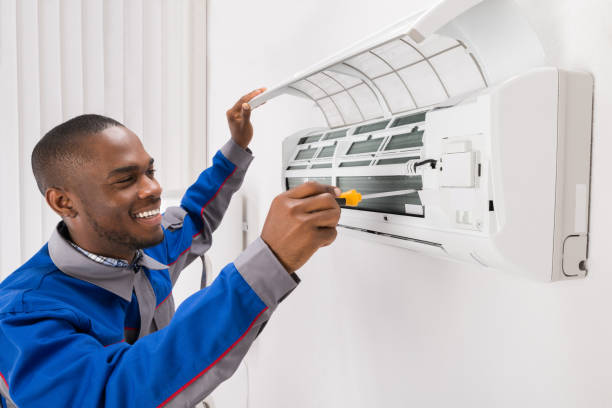 happy young african male technician repairing air conditioner