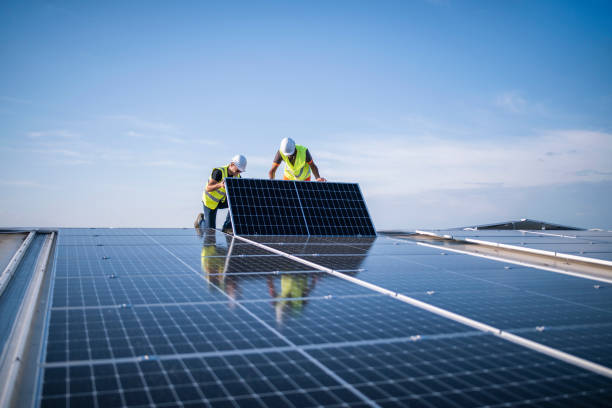 Solar Energy team of two engineers installing solar panels on industrial factory roof.